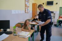 Policjant rozdaje uczniom testy